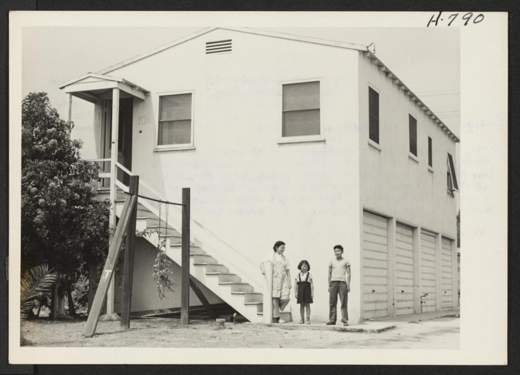 Three Japanese Americans stand outside a boarding house in Sawtelle, Los Angeles in 1945.