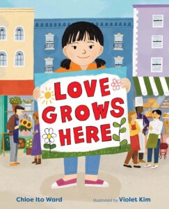 Book cover of Love Grows Here by Chloe Ito Ward. It shows an illustration of a young Japanese American girl standing on a city sidewalk holding up a colorful sign with the book's title.