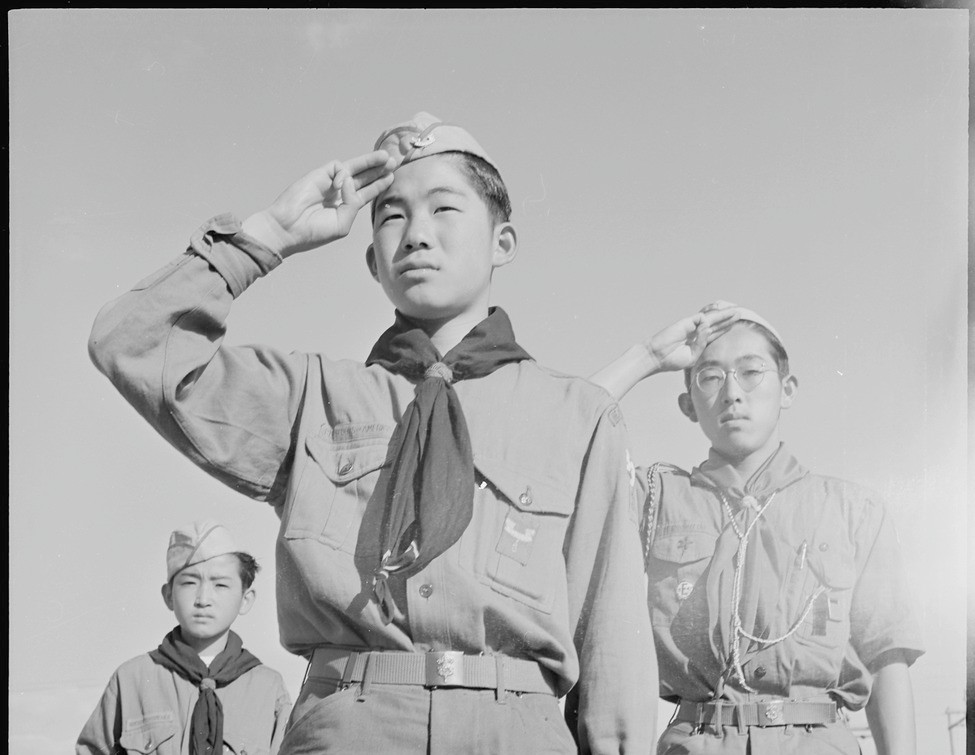 Three Japanese American Boy Scouts saluting the flag in Heart Mountain concentration camp.