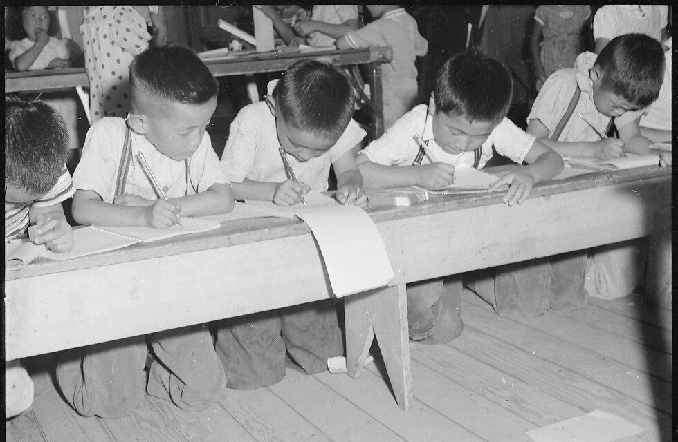 Elementary students studying in a makeshift classroom inside Manzanar, 1942.