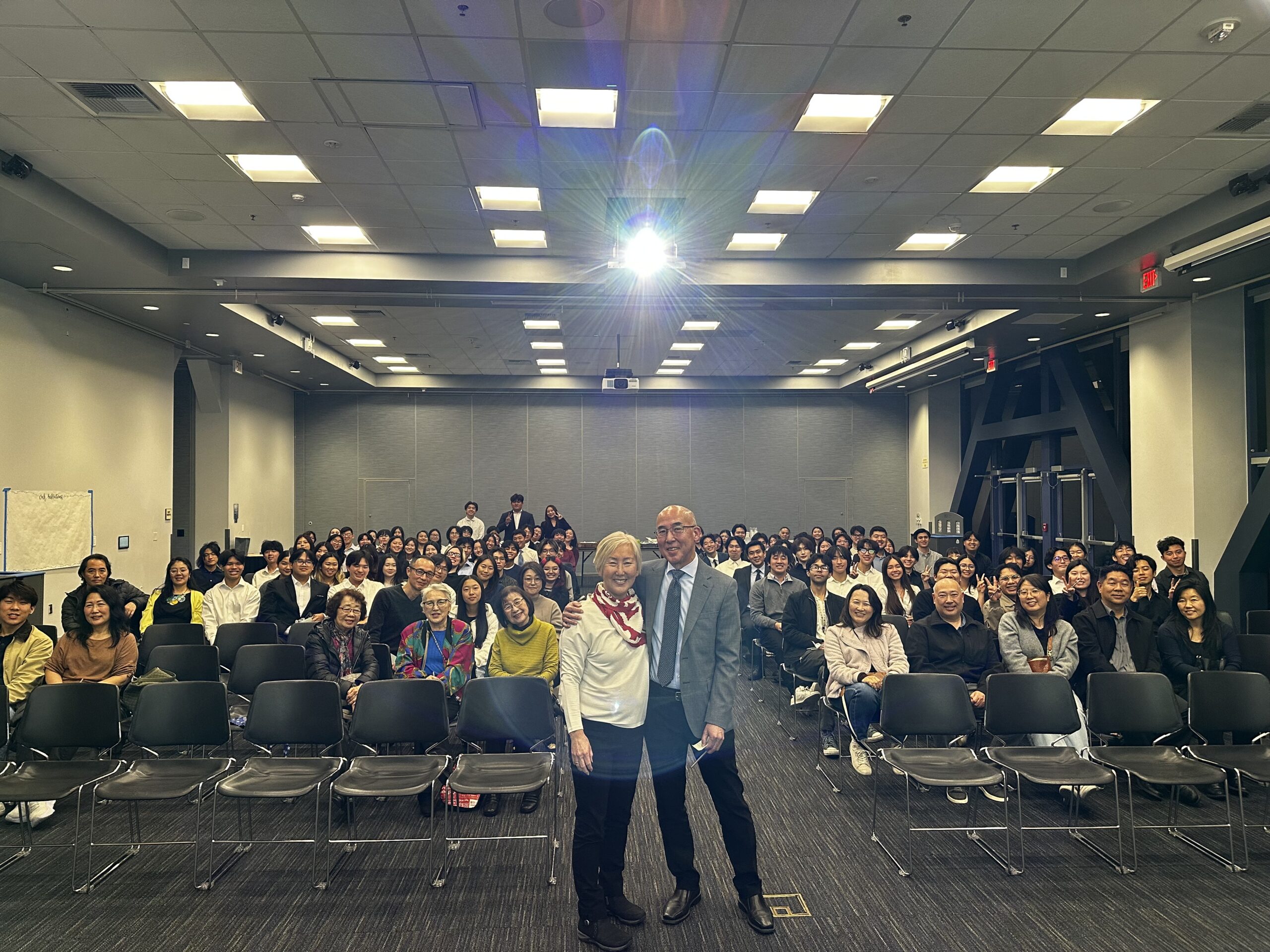 Brian Niiya (center right) with Karen Umemoto (center left) in front of attendees for UCI Tomo No Kai event. February 15, 2026, UC Irvine Student Center.
