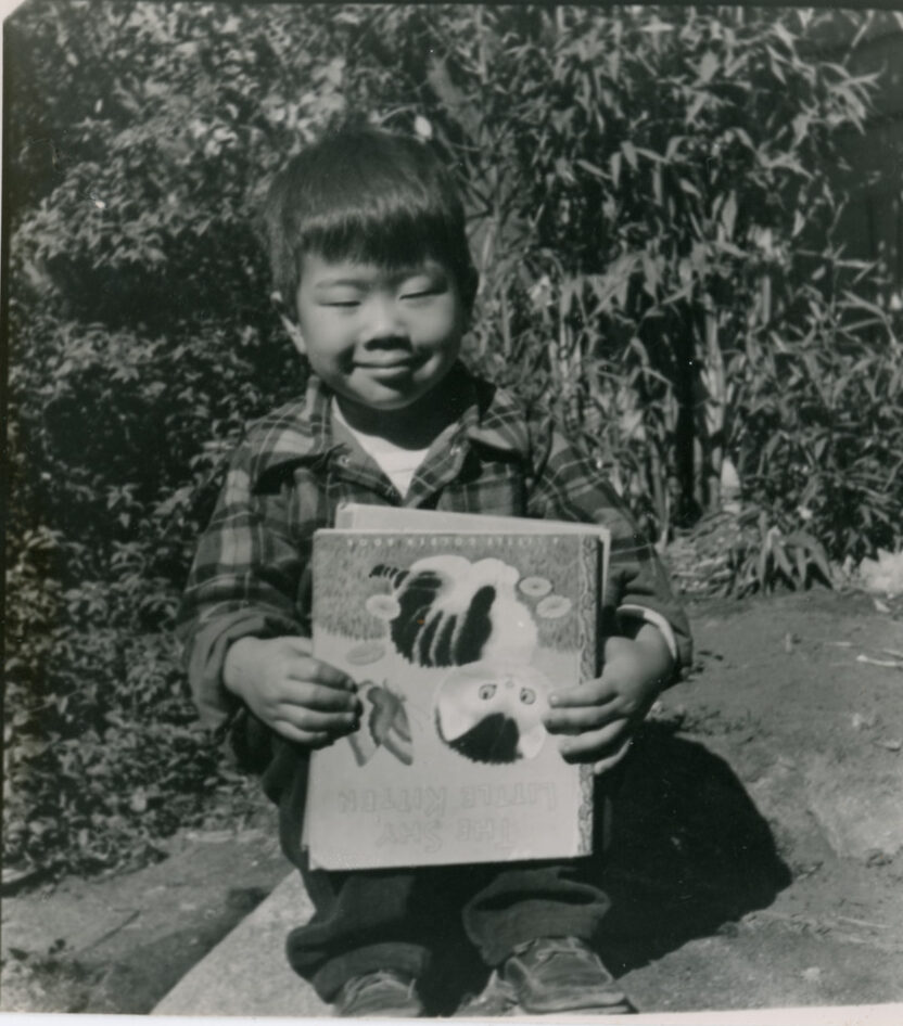 Little boy Norman Takahashi holding a book.

