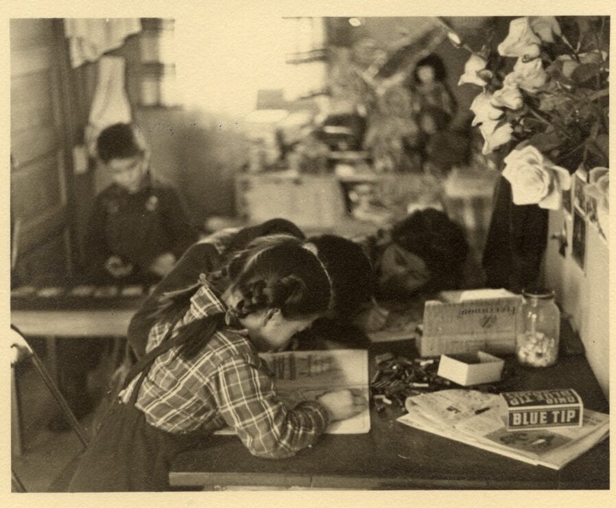 Black and white photo of children reading in WWII incarceration camp