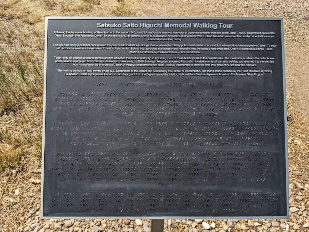 An interpretive sign at Heart Mountain with text with braille transcription below.