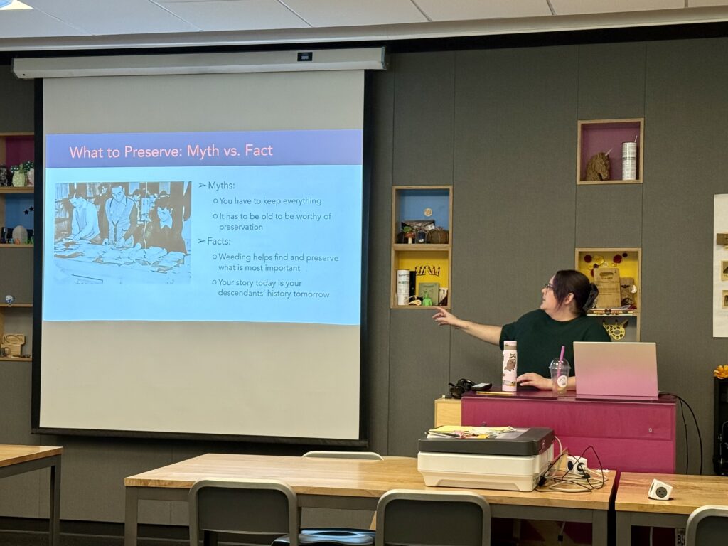 Densho archivist Micah Merryman stands in front of room and presents on selecting and preserving materials. Slide reads: "What to Preserve: Myth versus Fact."