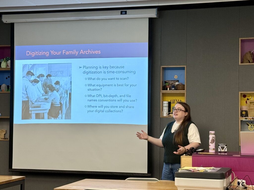 Densho archivist Sara Beckman stands in front of classroom and answers questions about digitization. Slide next to her reads: "Digitizing Your Family Archives"