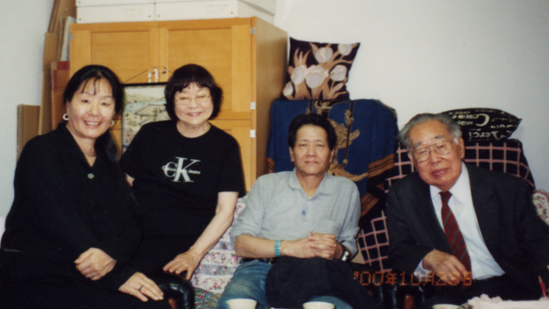Family photo of Masako, Tomoye, Norman (most likely) and Henri Takahashi, sitting in front of cabinet.