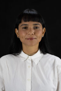 Headshot of woman in white shirt on black background.