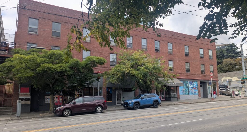 Exterior of brick building with two cars parked in front
