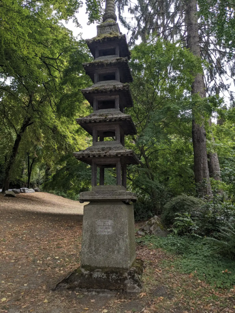 Color image of a tall Japanese lantern in a garden with green trees surrounding