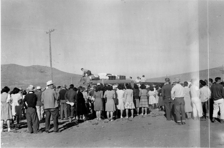 A crowd of Japanese Americans are waiting to board a bus