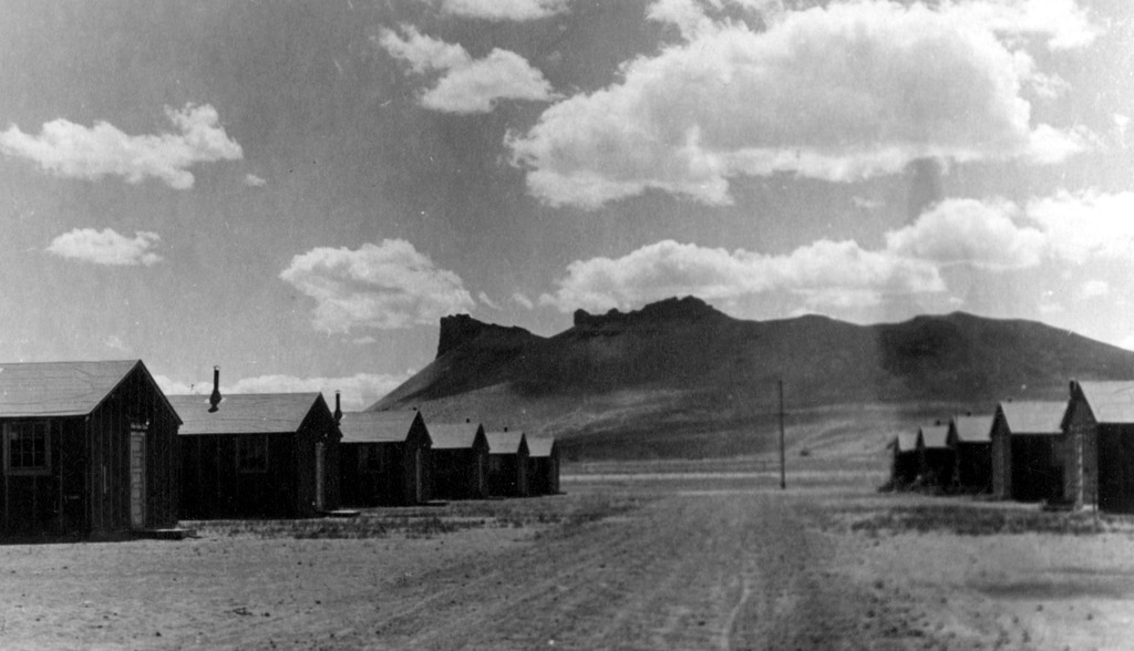Black and white landscape image of Castle Rock in the Tule Lake concentration camp. Barracks can be seen in the foreground.